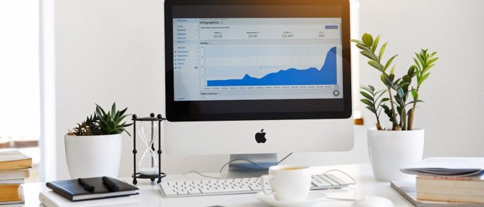 A clean, contemporary workspace featuring a desktop with analytics on the screen and plants for a fresh look.